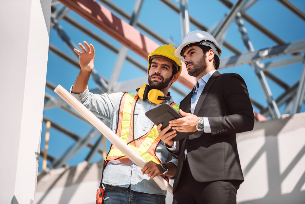 Servicios ingeniero civil y gerente de trabajadores de la construccion con tableta digital y planos hablando y planeando sobre el sitio de construccion concepto de trabajo en equipo de cooperacion
